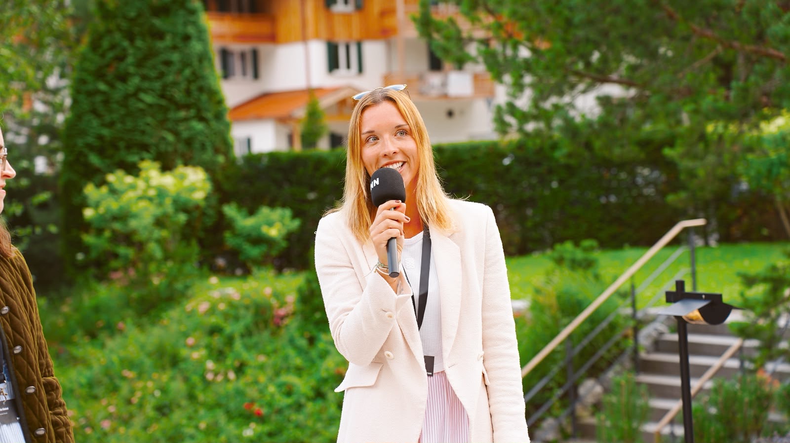Caroline Krinner moderating an outdoor event, smiling and holding a microphone